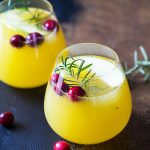 Two glasses of sangria garnished with cranberries and rosemary sprigs.