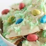 A closeup of white chocolate bark topped with robin eggs candy and green shredded coconut.