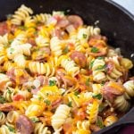 Spiral pasta with sausage and cheese in a cast iron skillet.