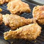 Fried chicken on a black wire baking rack on a baking sheet.