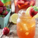 Beer lemonade in a mason jar garnished with a strawberry and lemon.