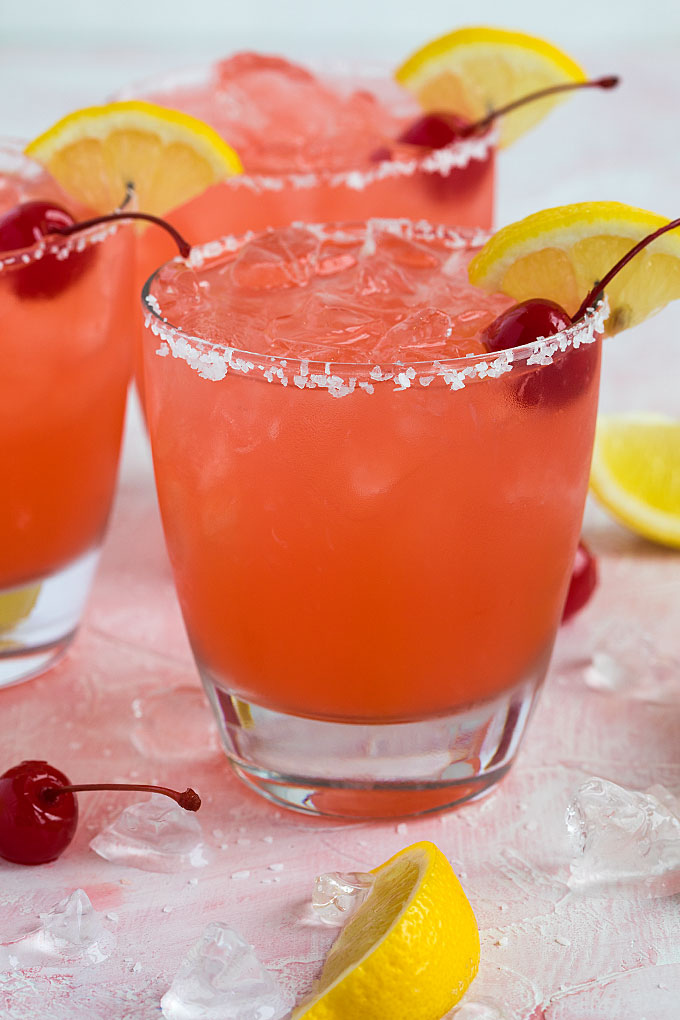Front closeup view of a cherry lemonade margarita in a salt-rimmed glass.
