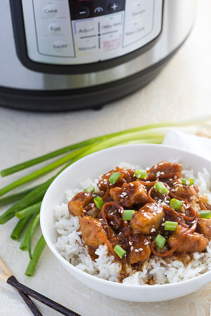 Mongolian chicken over rice in a white bowl.  An instant pot is in the background.