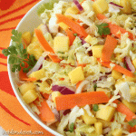 Overhead closeup of coleslaw with pineapple chunks in a white bowl.