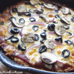 A closeup view of vegetable pizza in a cast iron skillet.