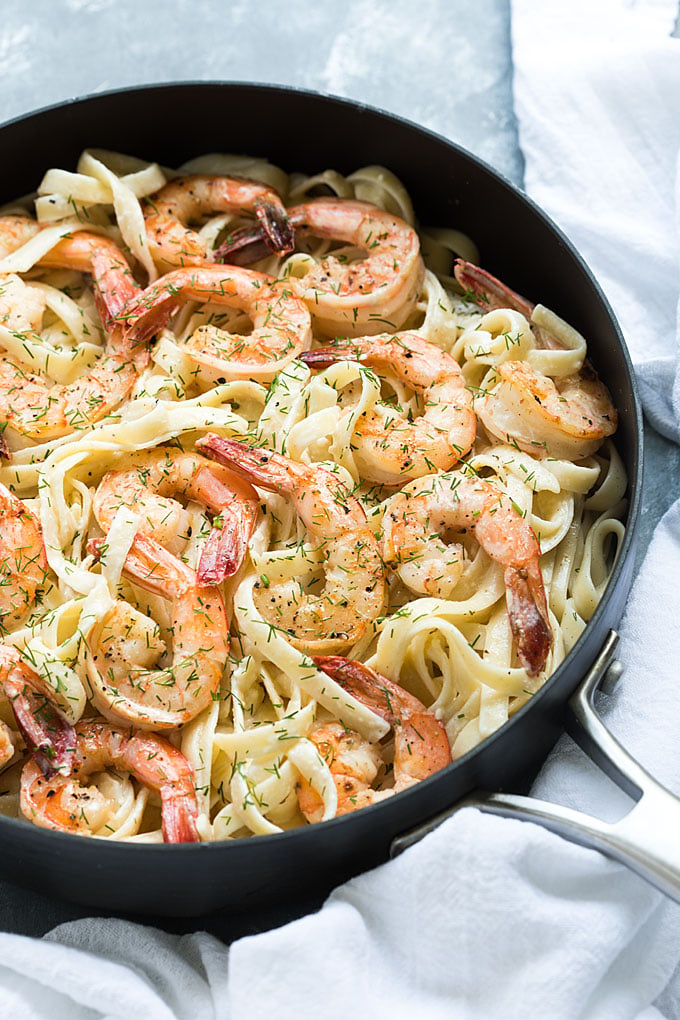 Closeup view of creamy pasta with shrimp and dill in a skillet.