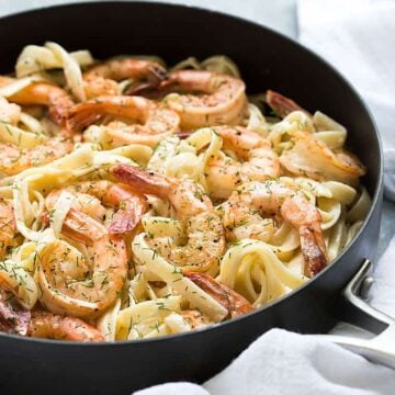 Creamy fettuccine with shrimp and dill in a skillet.