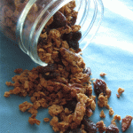 A glass jar on its side with granola coming out of the jar on a blue cloth napkin.