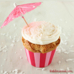 A cupcake in a pink striped liner with white frosting and a pink umbrella.