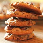 A stack of five cookies on a wood surface.
