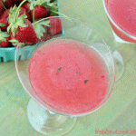 Overhead view of a strawberry martini with fresh basil pieces in it.