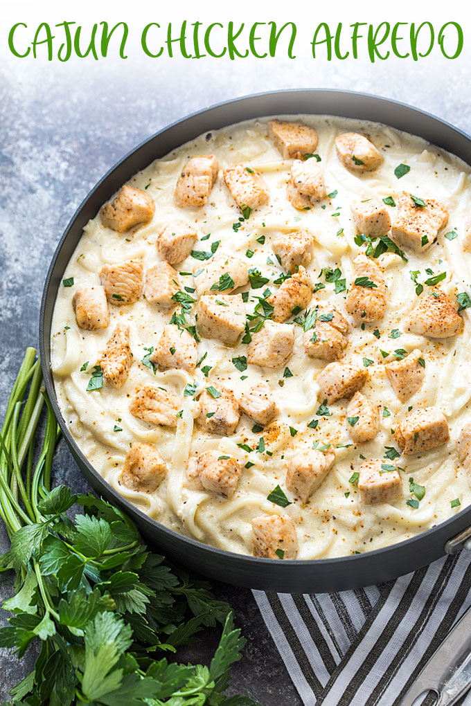Overhead view of Cajun chicken Alfredo in a skillet.  Overlay text at top of image.