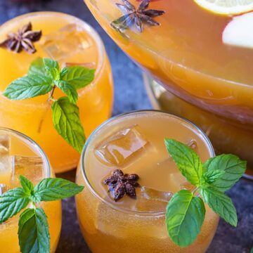 Overhead closeup of three glasses of punch garnished with mint and star anise.