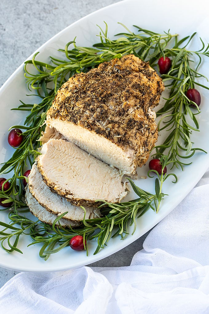 Overhead view of a partially sliced turkey breast on an oval white platter.