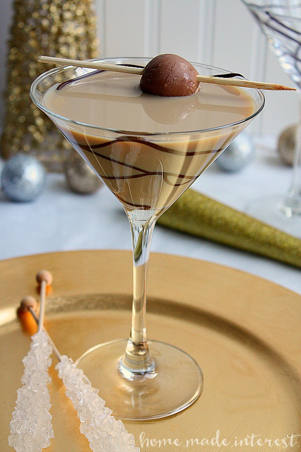A chocolate martini garnished with a piece of chocolate on a gold plate.