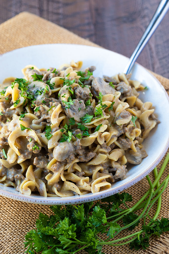 Stroganoff with ground beef and mushrooms in a white bowl with a fork.