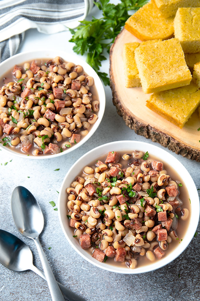 Black-eyed peas and ham in two white bowls.