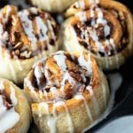Close-up of glazed cinnamon rolls in a cast iron skillet.