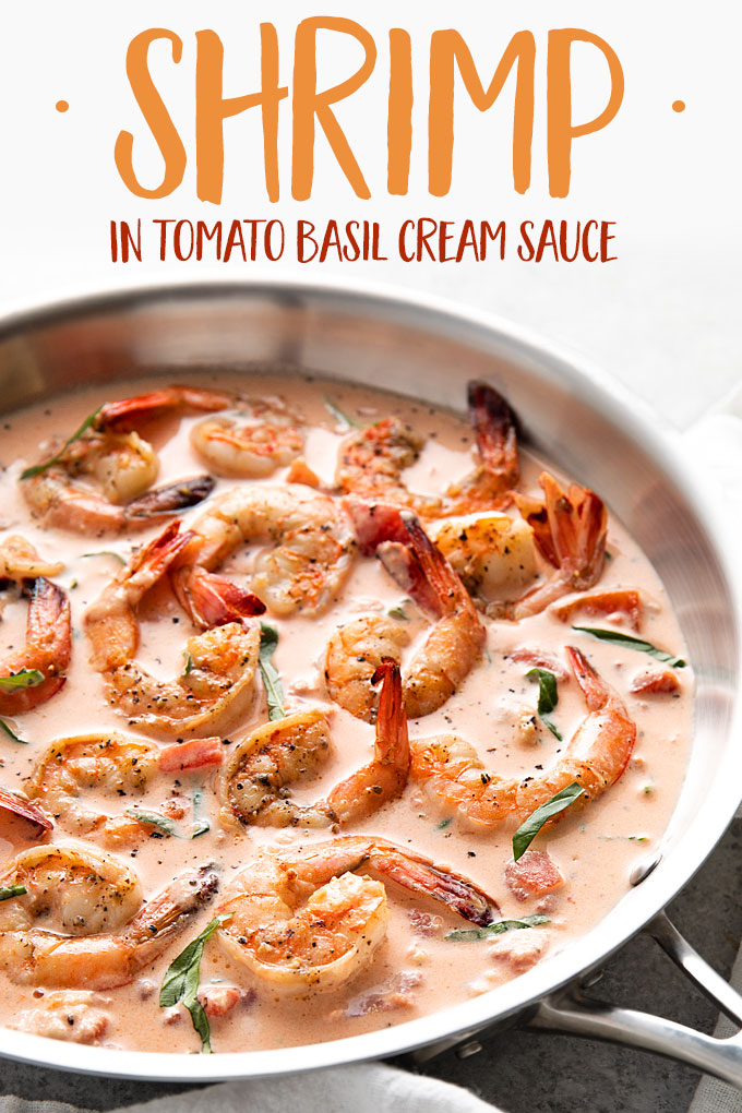Shrimp in a tomato basil cream sauce in a skillet beside a white kitchen towel.