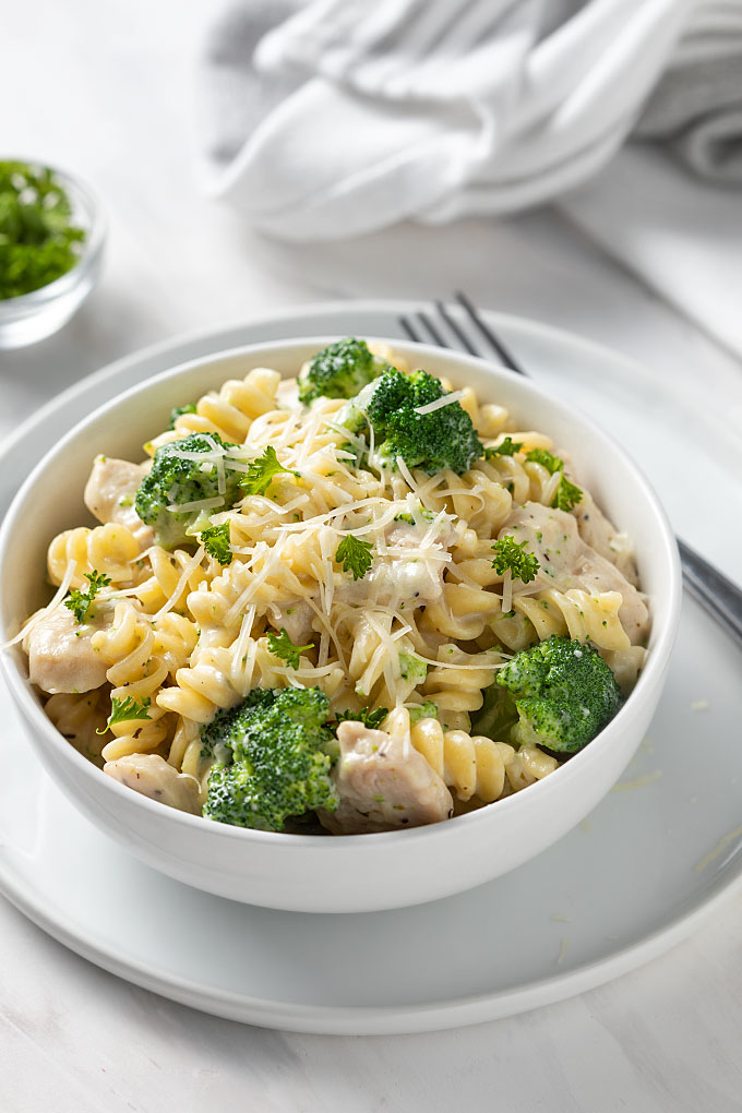 Chicken and Broccoli Alfredo in a white bowl on a white plate.