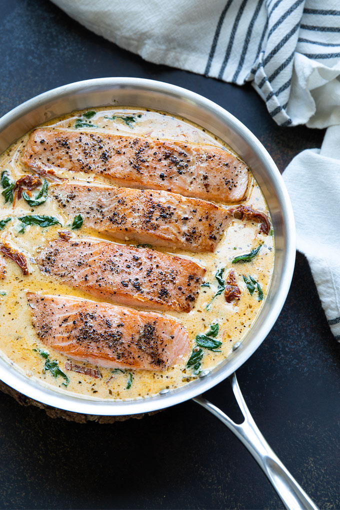Overhead view of creamy tuscan salmon in a stainless skillet.