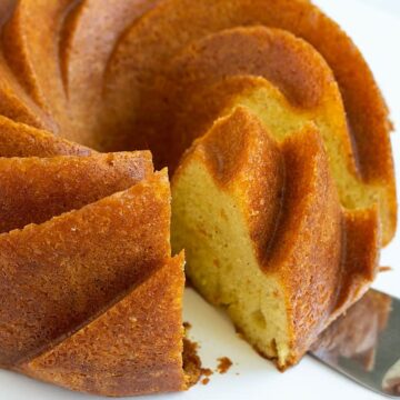 Spiced orange rum (bundt) cake on a round white serving platter that has been sliced with a serving knife.