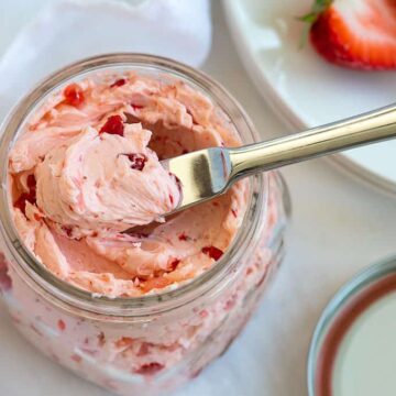 Overhead image of whipped strawberry honey butter in a pint mason jar with a spreading knife