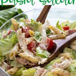 Closeup of chicken Caesar pasta salad in a glass bowl with overlay text.