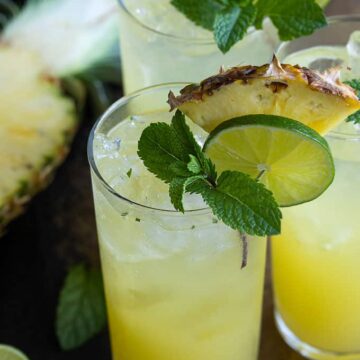 3 Pineapple Mojitos garnished with fresh pineapple, lime and mint