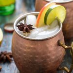 Two Apple Cider Mules garnished with apple, lime and a star anise