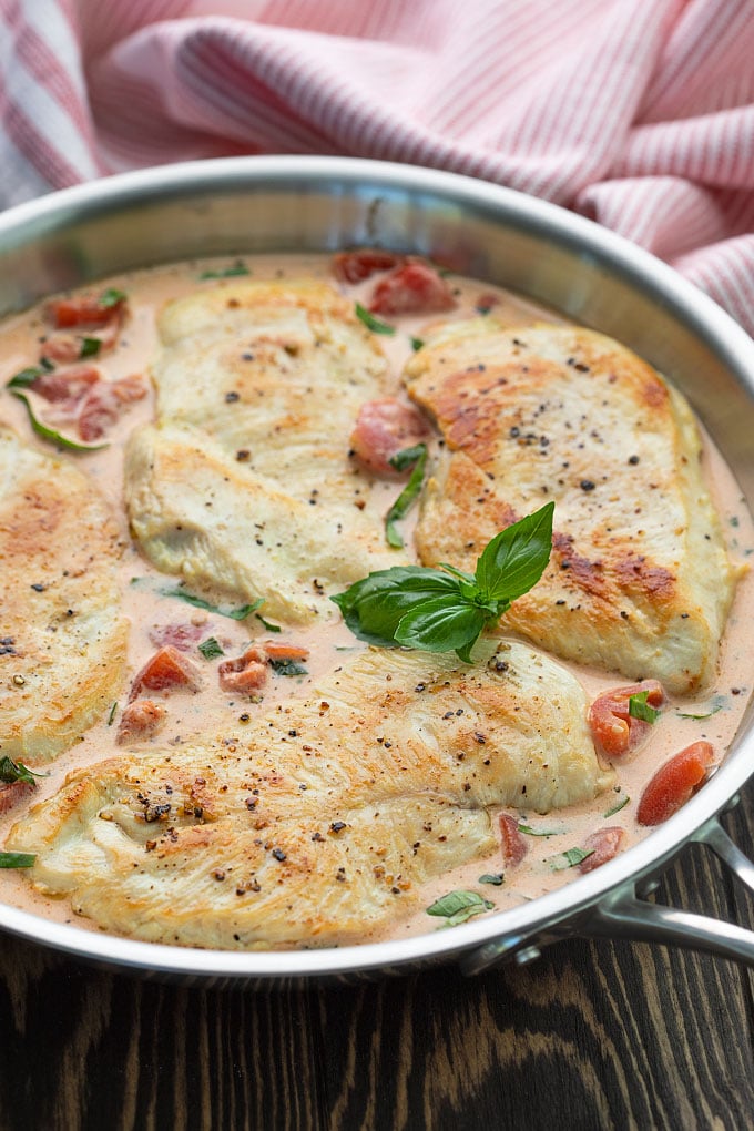 Chicken in a cream sauce flavored with tomatoes and basil in a skillet