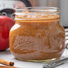 Applesauce in a glass Mason jar with a slow cooker in the background