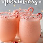 Three glasses of pink frozen cocktails garnished with candy canes.