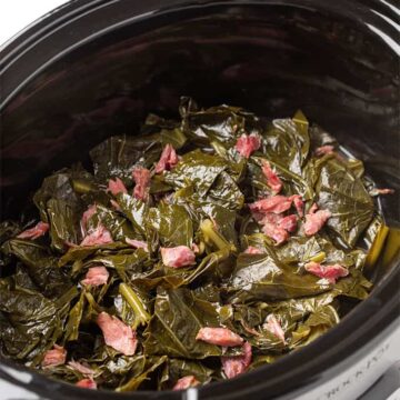 Collards and ham hocks in an oval slow cooker
