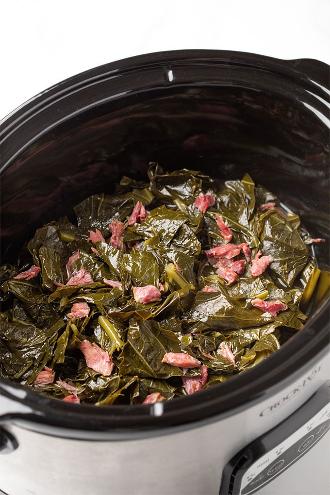 Collards and ham hocks in an oval slow cooker
