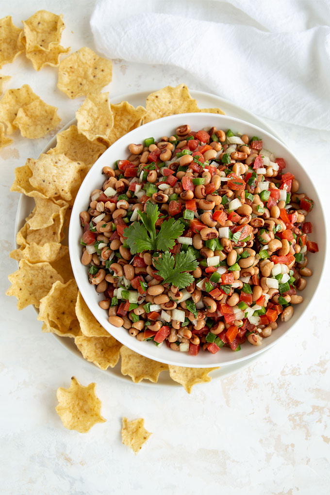 Overhead view of Black-Eyed Pea Salsa in a white bowl with tortilla chips
