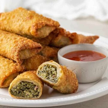 Collard egg rolls on a plate with sweet chili sauce