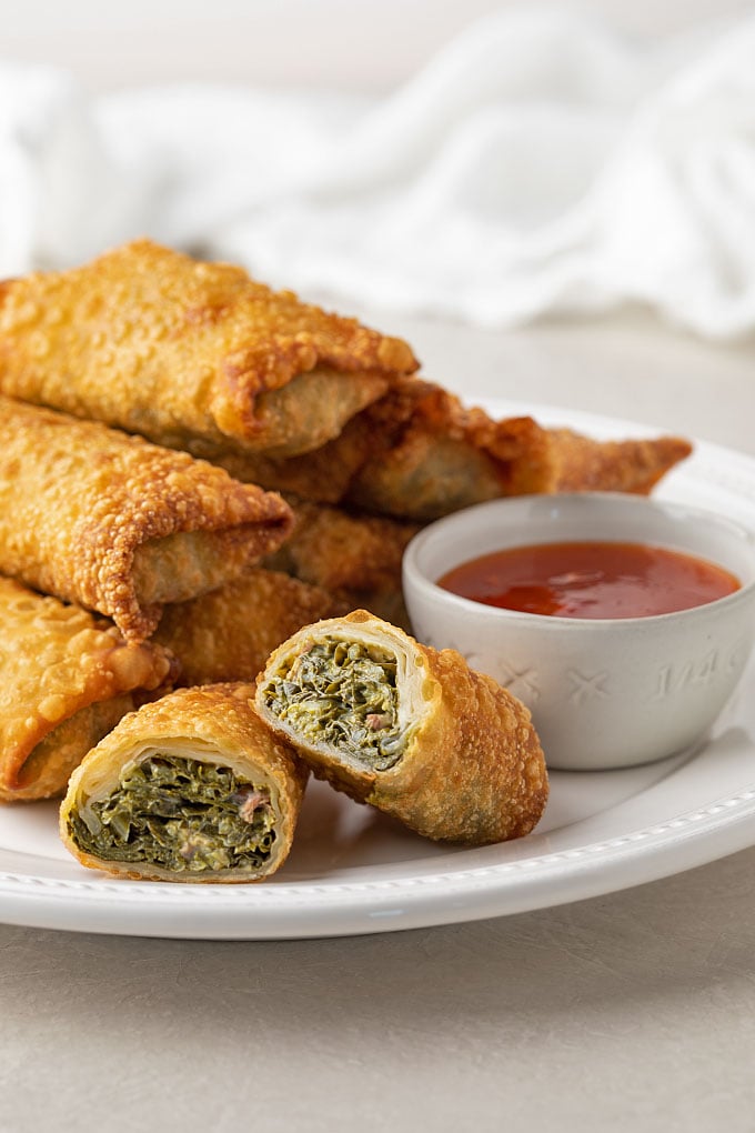 Collard egg rolls on a plate with sweet chili sauce