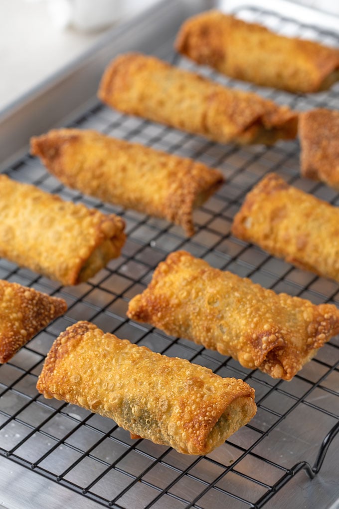 Collard green egg rolls on a wire rack placed over a baking sheet
