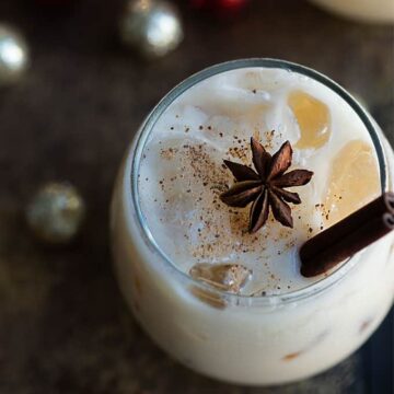 Overhead view of an eggnog white russian garnished with nutmeg, a star anise and cinnamon stick
