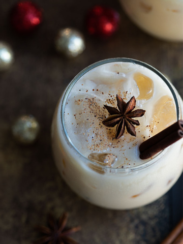 Overhead view of an eggnog white russian garnished with nutmeg, a star anise and cinnamon stick