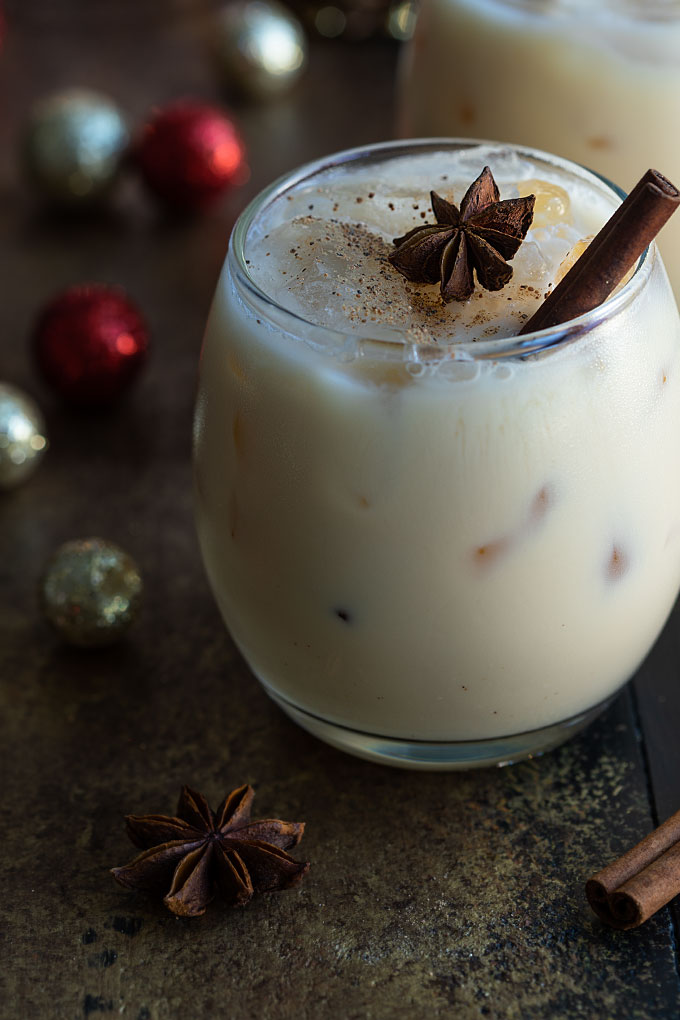 Front view of a white russian with eggnog in a glass with a cinnamon stick.