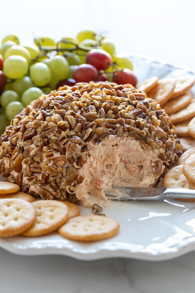 Shrimp cheese ball on a white serving platter with crackers and grapes