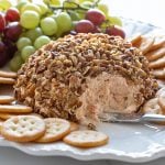 Shrimp cheese ball on an oval white serving platter with crackers and grapes