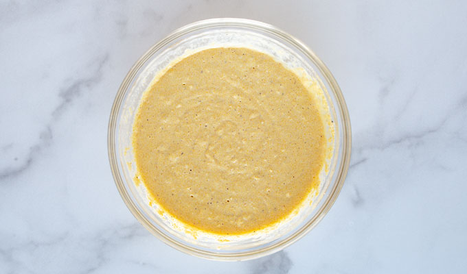 Overhead view of a glass bowl with cornbread batter