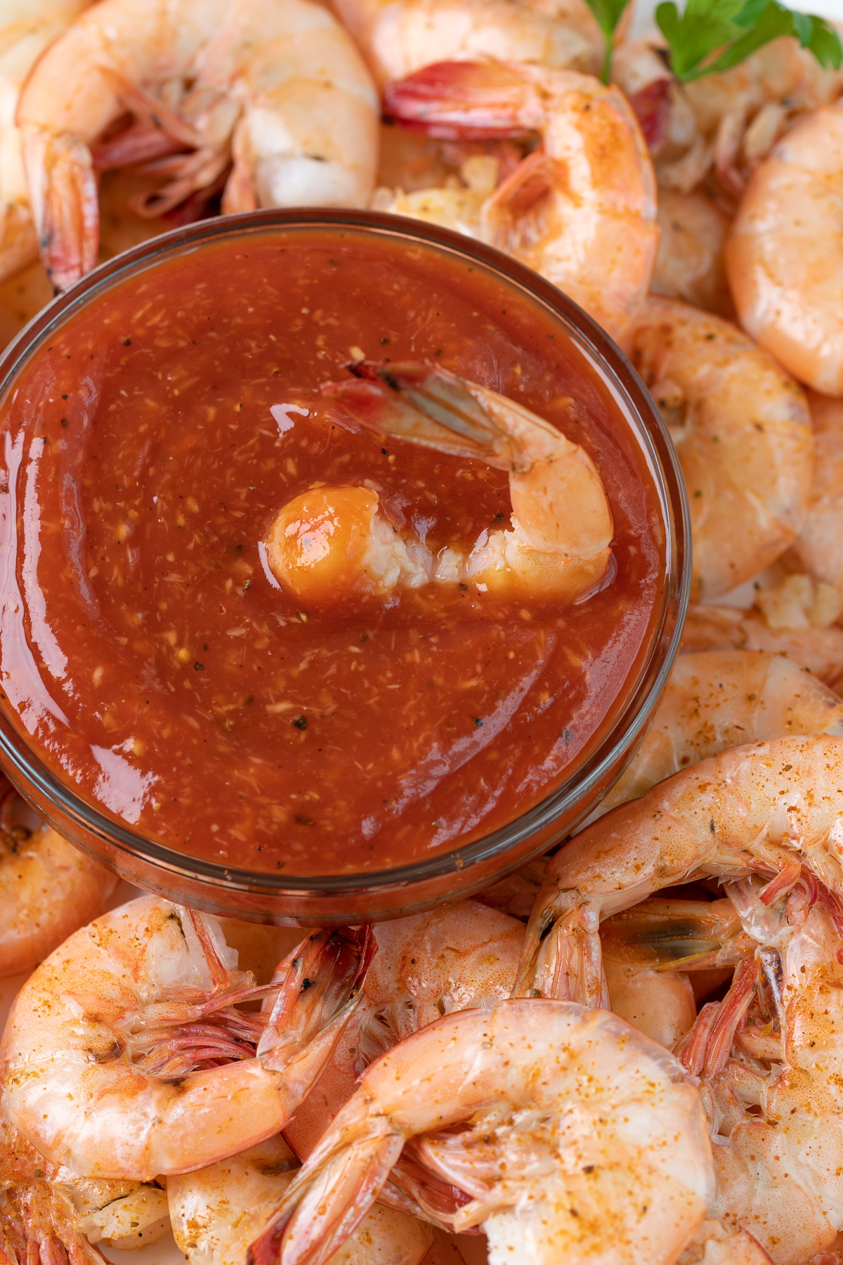 Overhead closeup view of a bowl of cocktail sauce surrounded by steamed shrimp.
