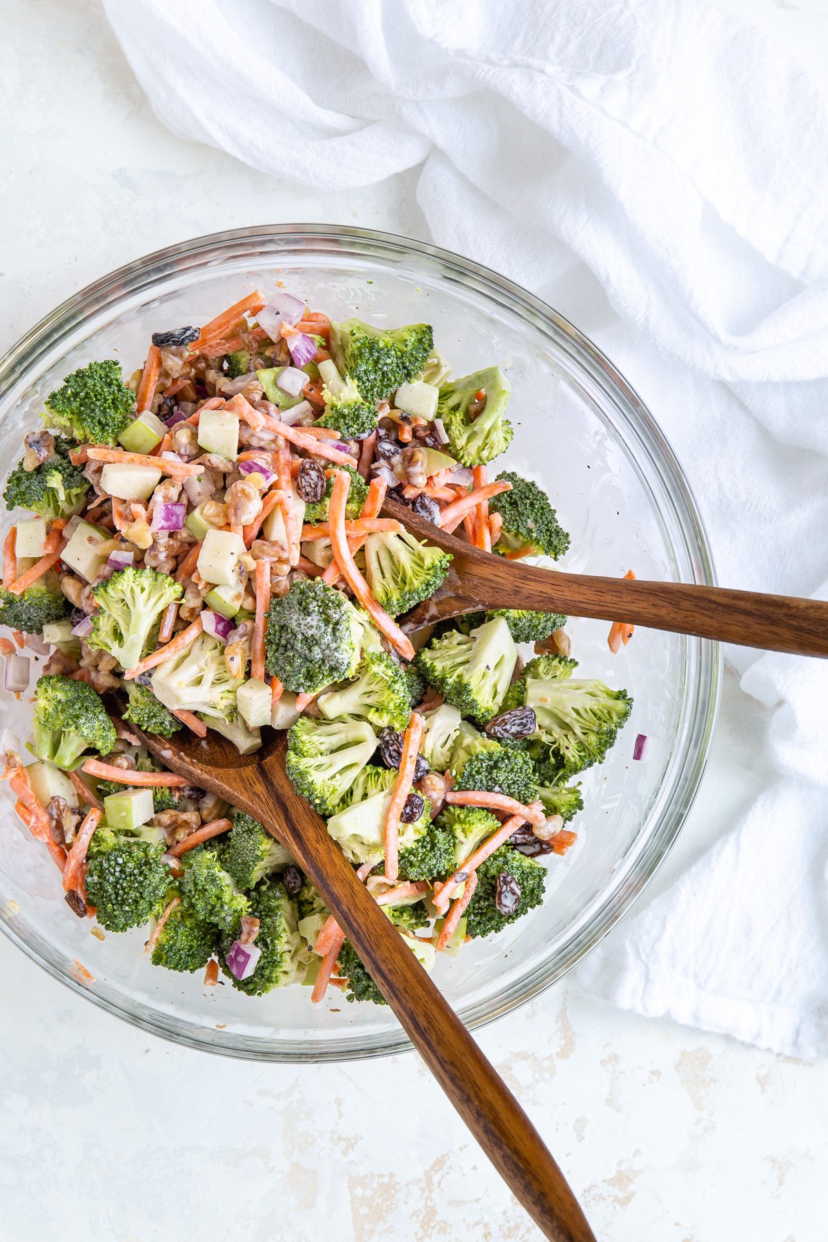 Overhead view of broccoli salad in a bowl with wooden salad servers.