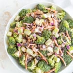 Broccoli salad in a white bowl. Overlay text at top of image.