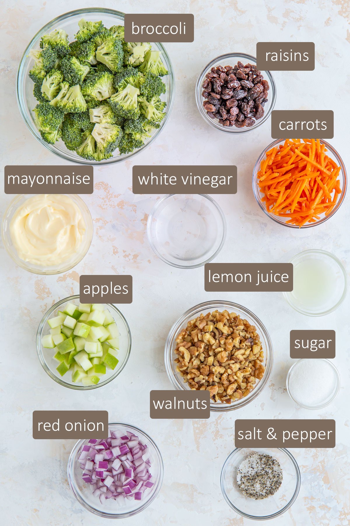Overhead view of ingredients for creamy broccoli salad in clear glass bowls.