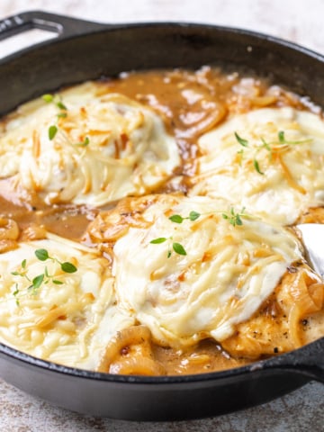 Closeup of French onion chicken in a cast iron skillet.